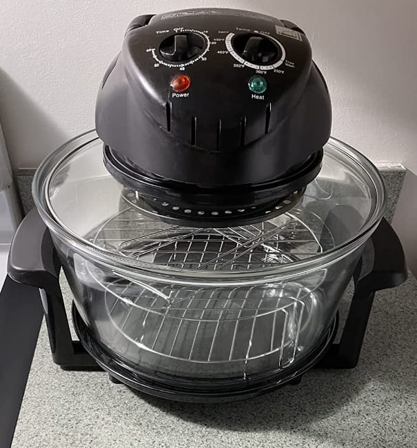 Image of the Nutrichef glass and stainless steel air fryer sitting in the corner of a gray countertop right next to stove