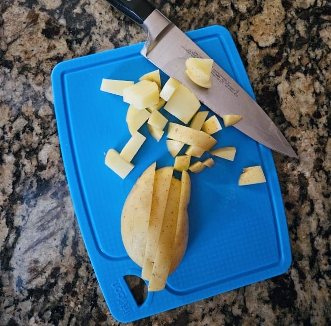 Image of a knife and chopped up onion sitting on a blue Liflicon Silicone Cutting Board