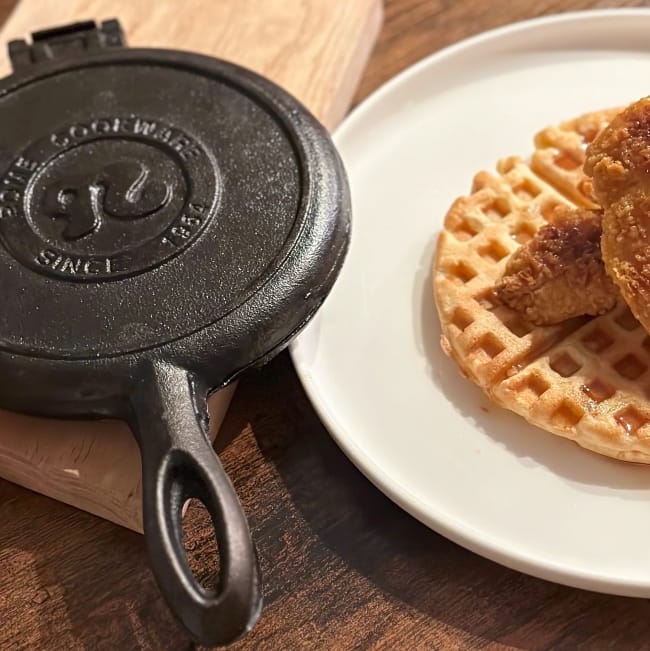 Rome-budget-friendly-cast-iron-waffle-iron sitting on table next to a plate of chicken and waffles