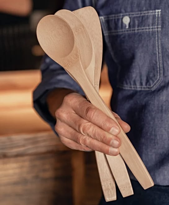 Image of a man wearing denim jacket holding Bambu bamboo cooking spoons up towards camera