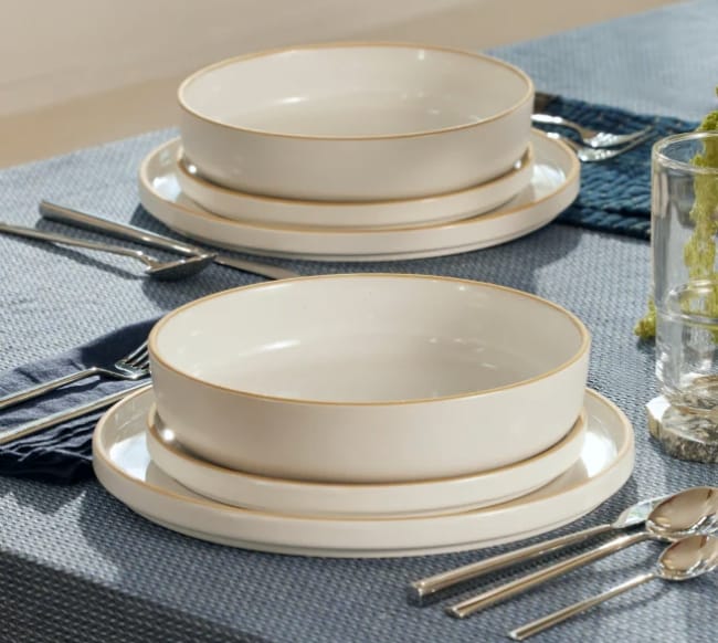 Our Place non toxic ceramic dinnerware plates and bowls displayed on table with cutlery and drinkware next to the dishes