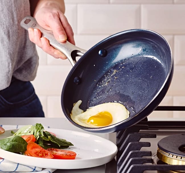 Image of man holding Blue Diamond nonstick pan without teflon with egg sliding out from oiled pan surface onto a white dinner plate