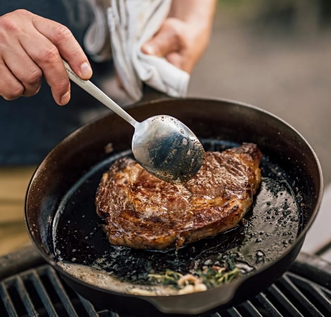 Image of man cooking a steak in a Field Company Cast Iron Skillet