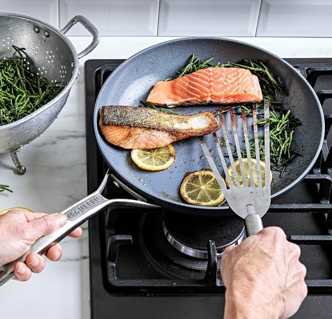 Image of a man cooking salmon on a gas stove with a GReenpan Paris Pro non-stick pan without Teflon