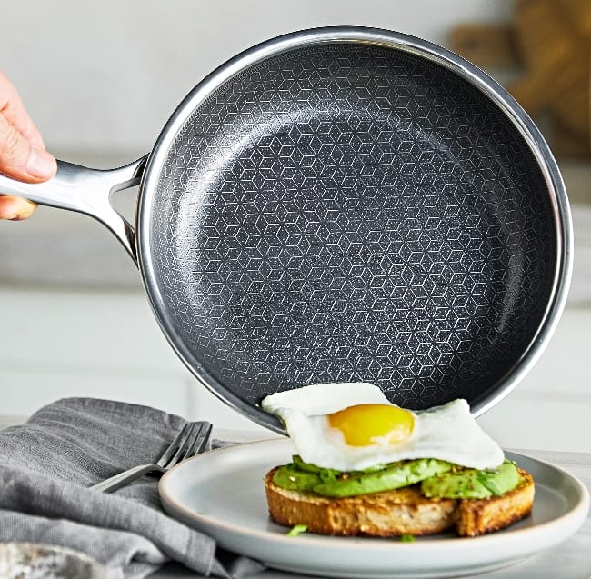 Image of Greenpan spectra held sideways with egg over easy sliding out onto a breakfast sandwich