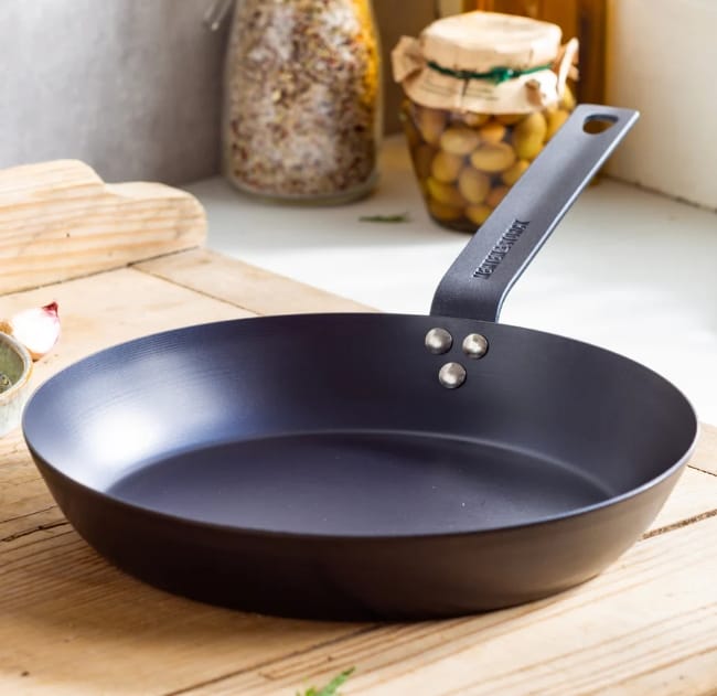 Image of an empty Merten & Storck carbon steel skillet sitting on wooden cutting board