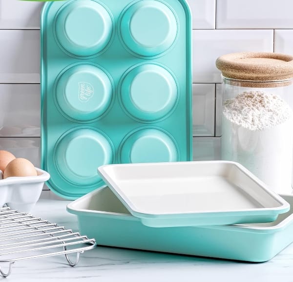 Greenlife-ceramic-non-stick-bakeware-set displayed on countertop with flour and eggs in the background and a cooling rack in the foreground