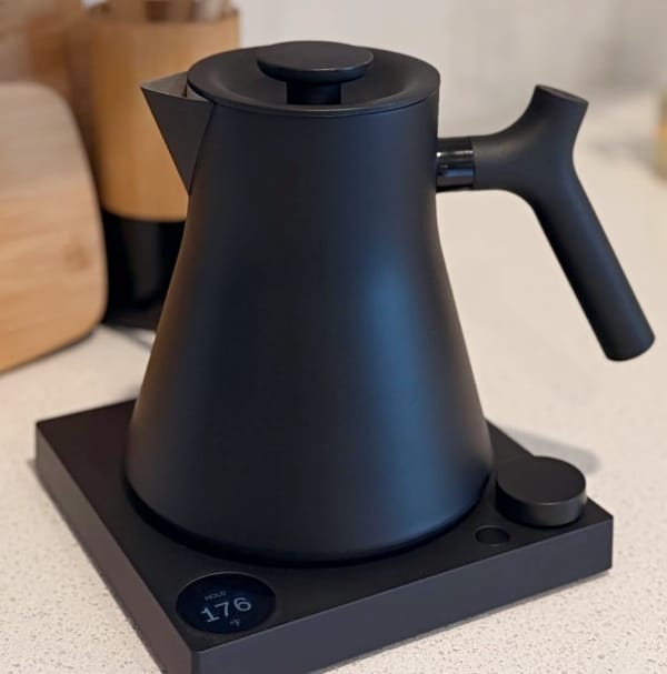 Fellow Corvo non toxic kettle on white countertop with wooden cooking utensils in the background